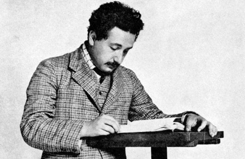 Einstein steht an einem Lesepult.