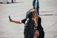 Eine Frau macht mit ihrem Smartphone ein Selfie von sich und einer Einstein-Statue.