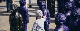 Ein kleines Kind berührt eine Einstein-Skulptur