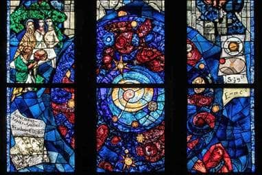 Ein Kirchenfenster zeigt verschiedene, aus Glassteinen zusammengesetzte Motive, unter anderem die fünf Wissenschaftler Kopernikus, Kepler, Galilei, Newton und Einstein.